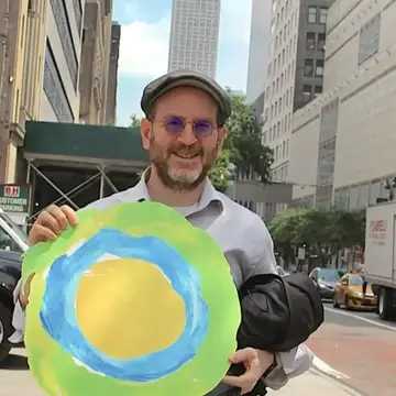 Um homem segurando o logo da Idealist posa na rua.