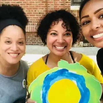 Três mulheres sorrindo com o logotipo da Idealist entre elas.