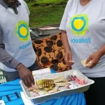 Duas pessoas trabalham atrás de uma mesa usando camisetas da Idealist.