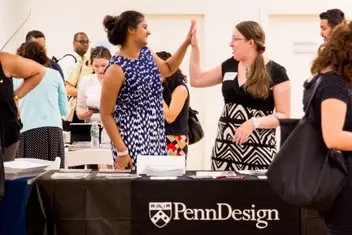 Two women from the Penn Design graduate program high-five each other.