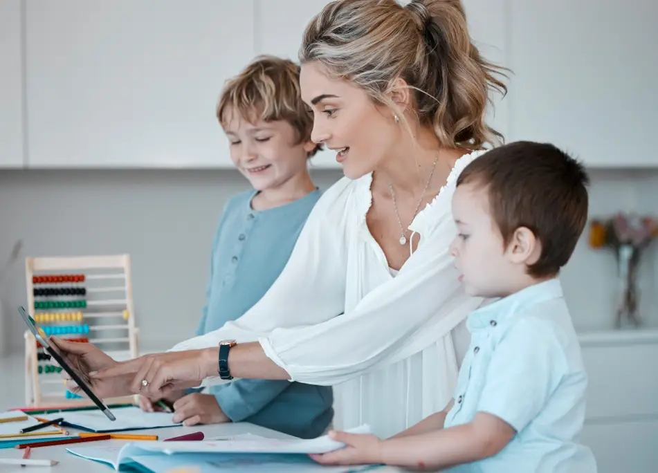 A mother working at a computer with her children on either side.