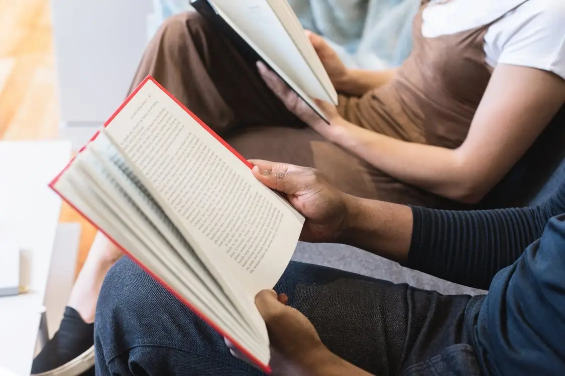 Two people reading books in a waiting room.